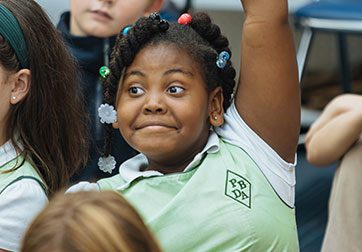 Photo of a student raising her hand. Links to Gifts That Pay You Income page.